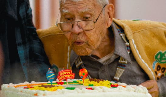 Chief Fred Ewan blowing birthday cake candles