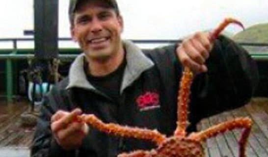 Photo of Sean Dunlap holding a King Crab and smiling at the camera