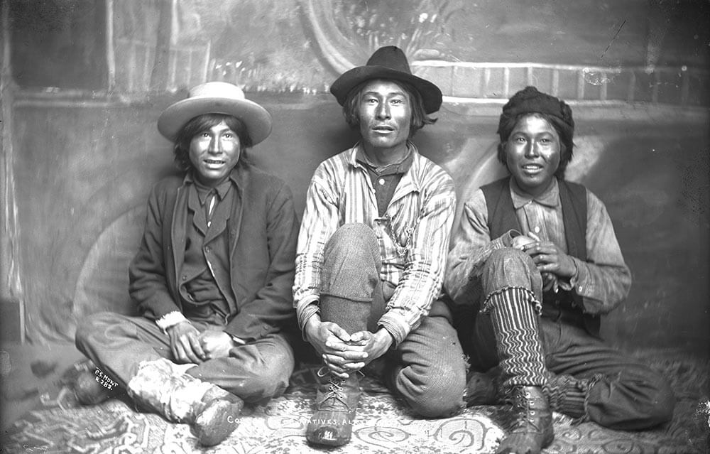 Old black and white photo of three man sitting on the floor, looking at the camera