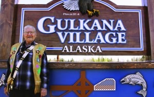 Photo of Fred Ewan in front of Gulkana Village sign, smiling at the camera