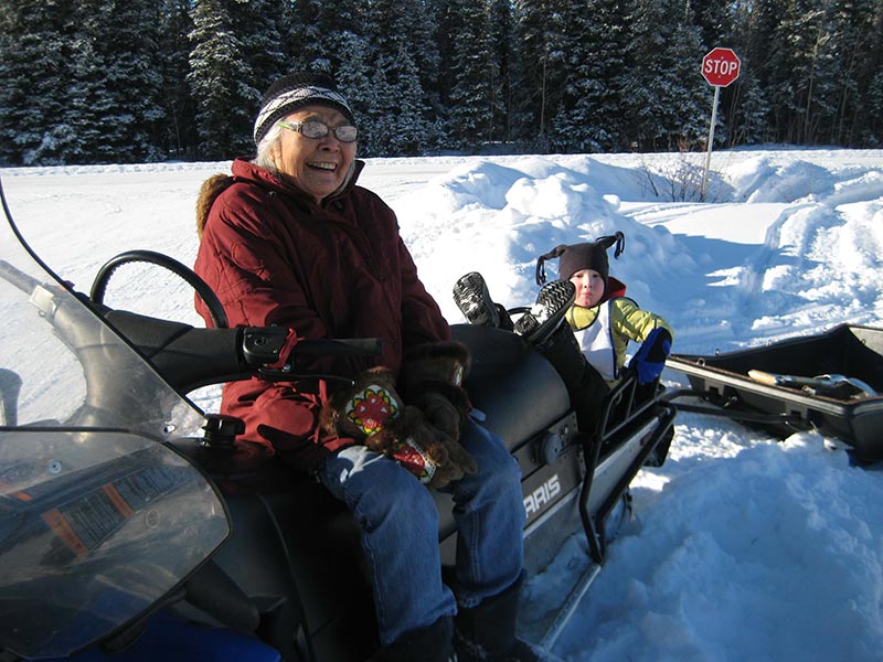 Photo of Lena sitting on snow machine, smiling and on the back of the machine