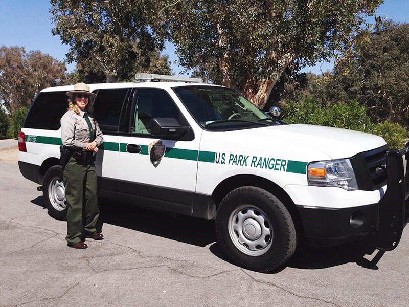 Photo of Ranger Heather wearing work uniform in front of Park Ranger vehicle