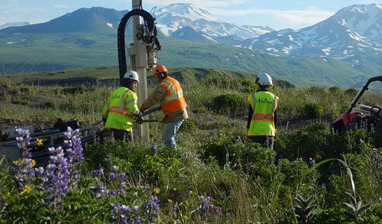 Ahtna workers drill in the beautiful Alaskan tundra with mountains in the background.