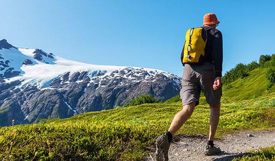 Hiker walks next to Alaskan glacier.