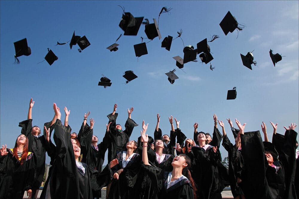 Photo of graduates throwing their cap in the air