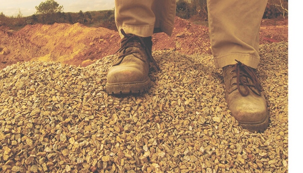 Low angle photo of man's work boots on rocks in sepia tones