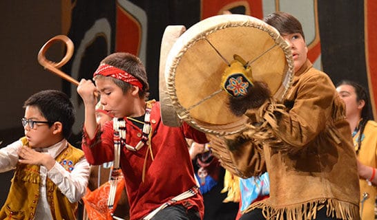 Children in traditional Alaska Native dress dancing and drumming.