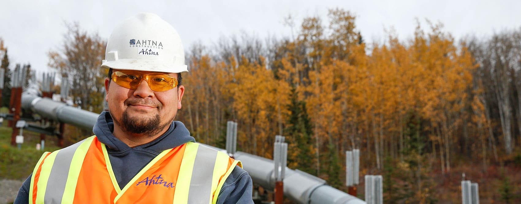 Ahtna worker in front of the Trans Alaska Pipeline.